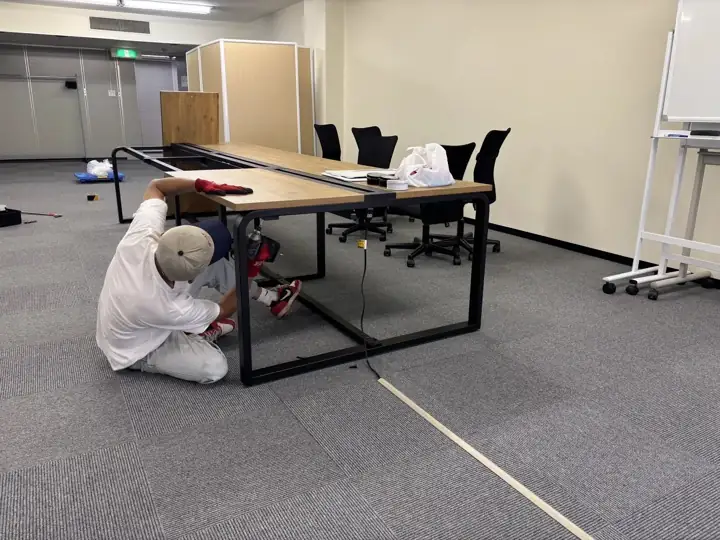 仙台市青葉区本町のオフィス家具回収事例:大型のワークテーブルを電動工具で分解している作業の様子