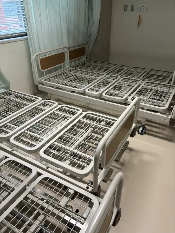病院の什器・設備の回収事例：病室に並べられた複数台の電動ベッドと、取り外されたベッド柵