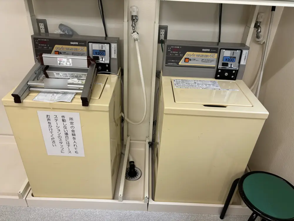 病院の什器・設備の回収事例：並んで設置された2台のコイン式洗濯機と排水パン